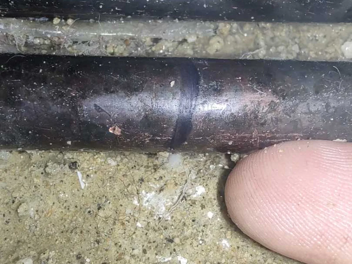 A corroded joint on the copper cold feed pipe, exposed in the concrete beneath the bathroom floor