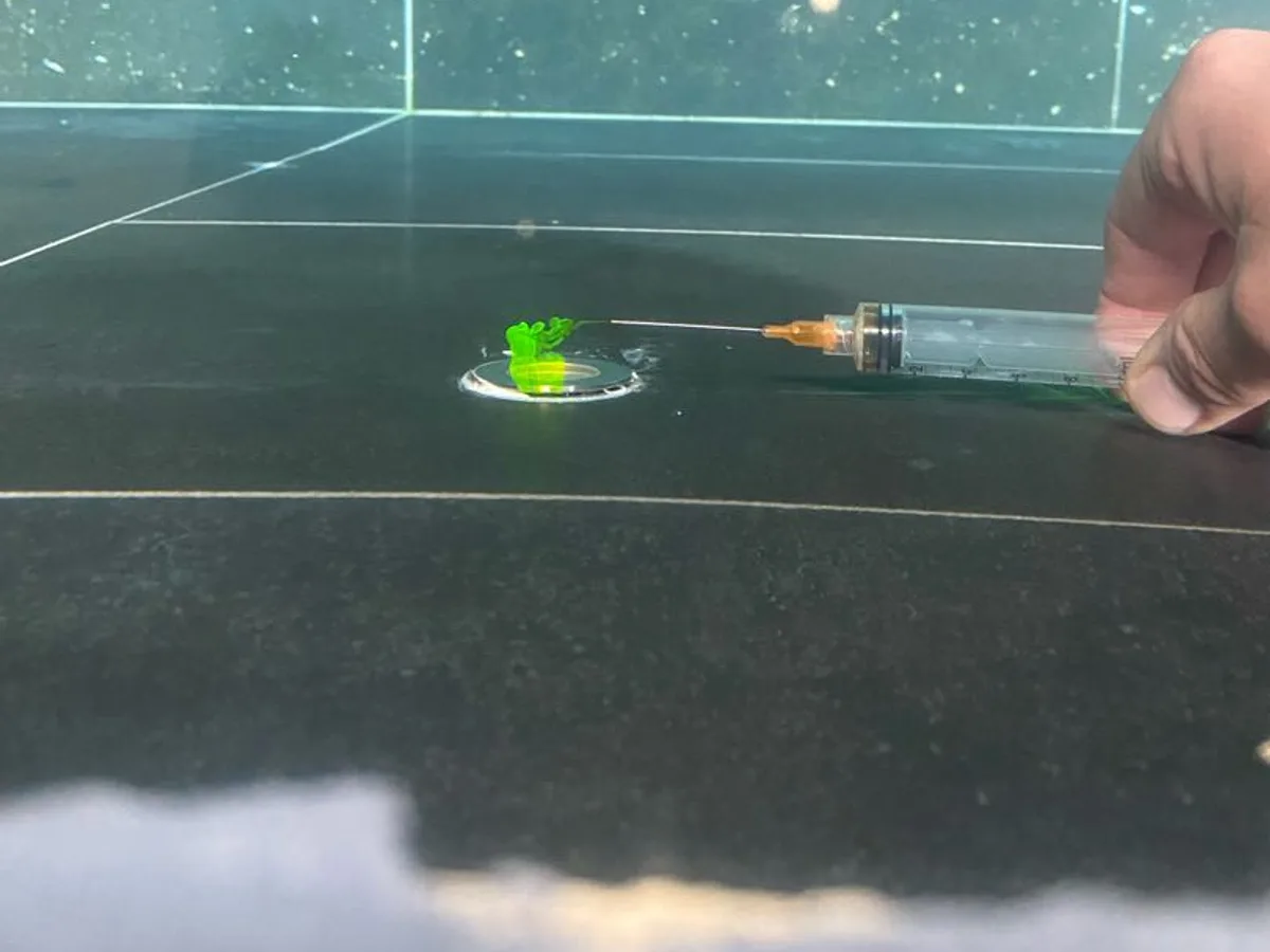 Green dye being drawn into the underwater pool light fitting during the dye test