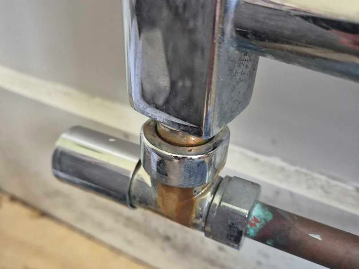 The chrome towel radiator valve, corroded and weeping at the compression joint