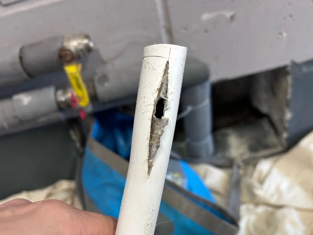 The split in the 22 mm PEX underfloor heating pipe, cut out and held up to the camera